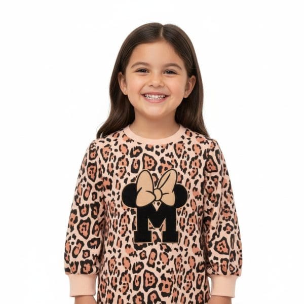 Niña sonriendo con vestido de animal print y logo de Minnie Mouse.