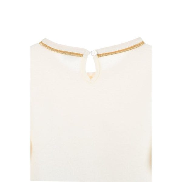 Detalle de blusa blanca con borde dorado y cierre en la parte superior.