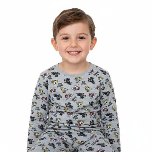 Niño sonriendo con ropa de manga larga con estampado de personajes de dibujos animados.
