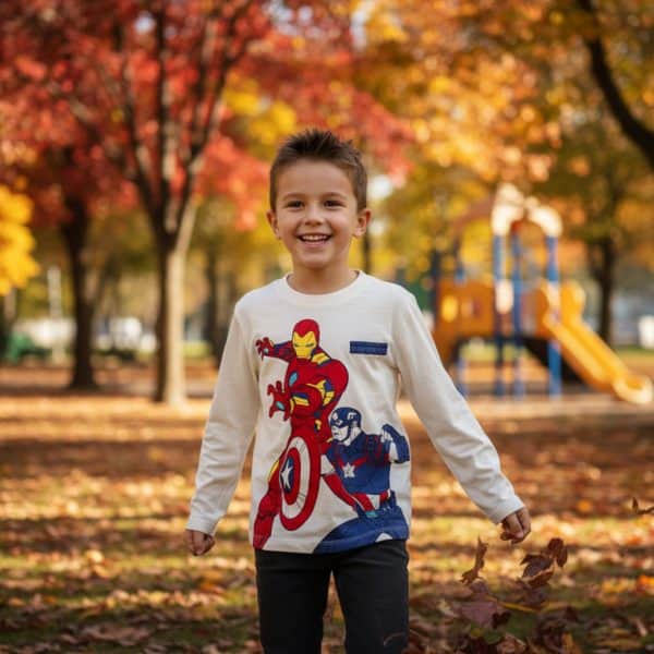 Niño sonriendo con ropa de superhéroes en parque de otoño.