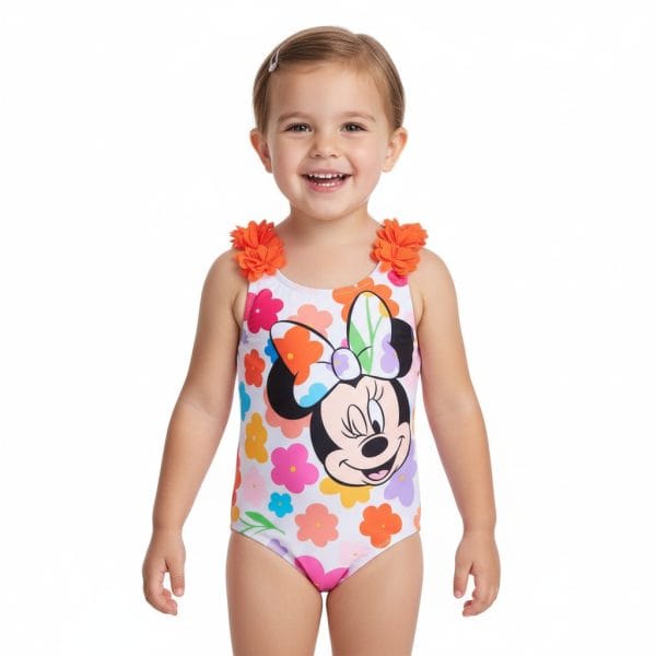 Niña sonriendo con bañador de Minnie Mouse y flores naranjas en los hombros.